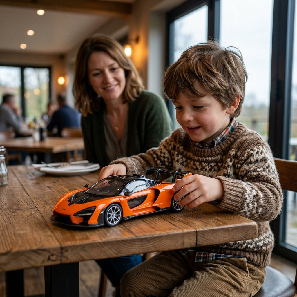 Metalni autić McLaren Senna 1:24 na drvenom stolu u restoranu dok se dete igra